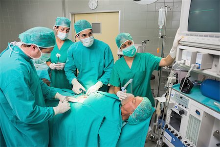 simsearch:400-06735487,k - Surgeon looking at a monitor while operating in an operating theatre Fotografie stock - Microstock e Abbonamento, Codice: 400-06735582