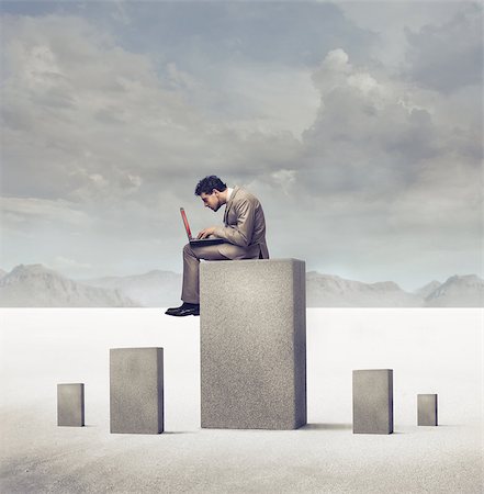 Businessman using a laptop on a concrete block in a desert Photographie de stock - Aubaine LD & Abonnement, Code: 400-06735884