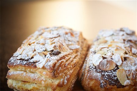 Fresh chocolate and Almond rollover croissant pastry, sprinkled with icing sugar on a brown wooden serving board with copy space  - Shallow Depth of Field (DOF) Stock Photo - Budget Royalty-Free & Subscription, Code: 400-06739260