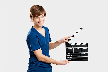 Casual young man holding a clapboard, over a gray background Photographie de stock - Aubaine LD & Abonnement, Code: 400-06739918