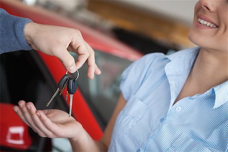 Smiling woman receiving keys from somebody in a car shop Stock Photo - Budget Royalty-Free & Subscription, Code: 400-06733576
