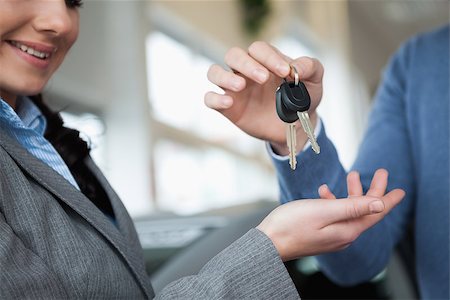 Smiling woman receiving keys from a hand in a car shop Stock Photo - Budget Royalty-Free & Subscription, Code: 400-06733571