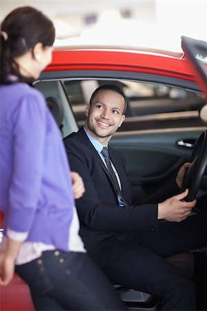 Man sitting in a car while talking to a woman in a car shop Stock Photo - Budget Royalty-Free & Subscription, Code: 400-06733686