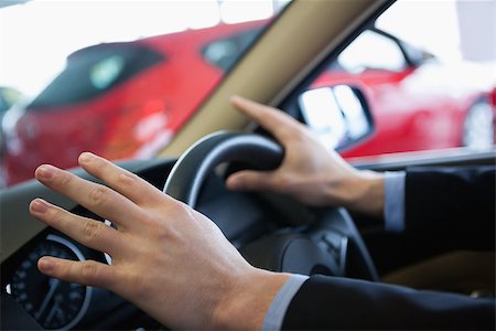 propietario de coche (hombre y mujer) - Man holding a steering wheel in a car dealership Foto de stock - Super Valor sin royalties y Suscripción, Código: 400-06733696