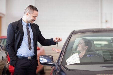 Salesman smiling while giving keys to a woman in a car dealership Stock Photo - Budget Royalty-Free & Subscription, Code: 400-06733735