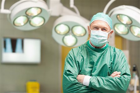 simsearch:400-06734621,k - Smiling surgeon crossing his arms while standing in a surgical room Stock Photo - Budget Royalty-Free & Subscription, Code: 400-06733969