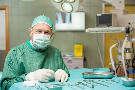 simsearch:400-06734621,k - Surgeon sitting next to a table full of a surgical tools in a surgical room Stock Photo - Budget Royalty-Free & Subscription, Code: 400-06733975