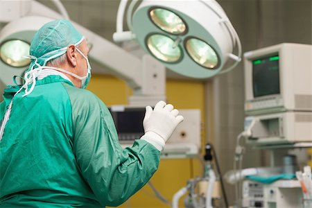 simsearch:400-06734621,k - Surgeon wearing surgical equipment raising his arm in a surgical room Stock Photo - Budget Royalty-Free & Subscription, Code: 400-06733979