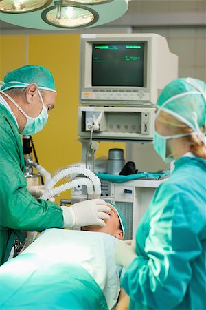 simsearch:400-06734621,k - Patient lying on an operating table with two surgeons in a surgery room Stock Photo - Budget Royalty-Free & Subscription, Code: 400-06733993