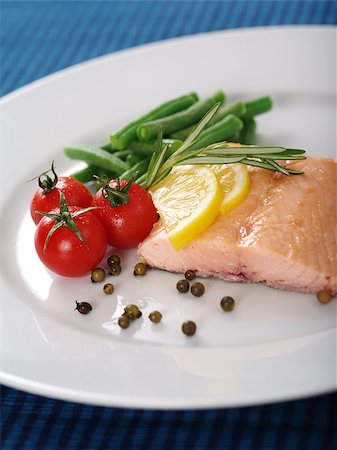 simsearch:400-07293364,k - Photo of a cooked salmon steak with rosemary, lemon slices, cherry tomatoes, green beans, and peppercorns on a white plate. Fotografie stock - Microstock e Abbonamento, Codice: 400-06743346