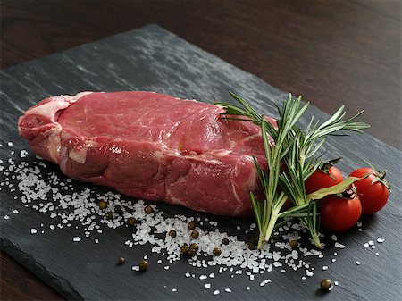 Photo of a raw thick sirloin steak with rosemary, cherry tomatoes, salt and peppercorns on a piece of black slate. Stock Photo - Budget Royalty-Free & Subscription, Code: 400-06743348