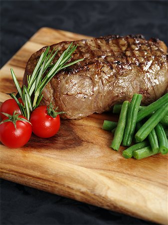 restaurant steak - Photo of a thick sirloin steak dinner with rosemary, cherry tomatoes and green beans on a wooden board. Stock Photo - Budget Royalty-Free & Subscription, Code: 400-06743351