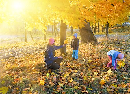 Happy family (mother with small children) walking in golden maple autumn park and sunshine behind the tree foliage Foto de stock - Super Valor sin royalties y Suscripción, Código: 400-06766945