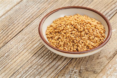 simsearch:400-07982929,k - gold flax seeds in a small ceramic bowl against a grunge wood surface Stockbilder - Microstock & Abonnement, Bildnummer: 400-06761915
