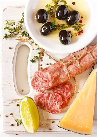 simsearch:400-07260354,k - Sliced salami, cheese and olive oil dip on a white board. Stockbilder - Microstock & Abonnement, Bildnummer: 400-06763917