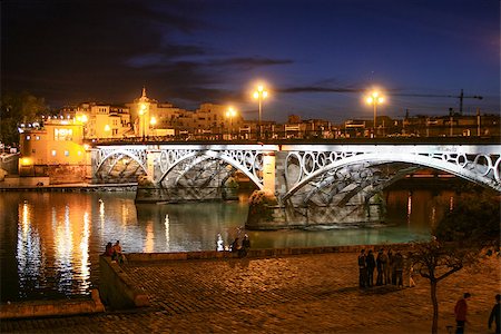 The Bridge of Triana over the river Guadalquivir, by night. This bridge was built from 1845 to 1852. Also known as the Bridge of Isabel II, it's one of the oldest iron bridges in Europe and leads to the famous neighbourhood of Triana. Foto de stock - Super Valor sin royalties y Suscripción, Código: 400-06770153