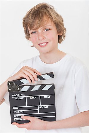 White background studio photograph of young happy boy smiling hand holding a filmmaker's clapperboard Stock Photo - Budget Royalty-Free & Subscription, Code: 400-06772406