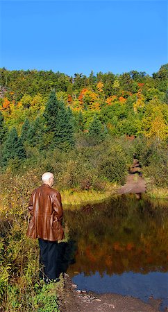 Adult male stands in front of pool and abandoned road.  Road leads to Cliff Copper Mine in Upper Penninsula, Michigan.  Autumn color reflects in pool and colors hillside. Stockbilder - Microstock & Abonnement, Bildnummer: 400-06787381