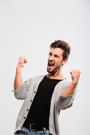 simsearch:400-04343310,k - Happy young man with arms up, over a gray background Photographie de stock - Aubaine LD & Abonnement, Code: 400-06788390