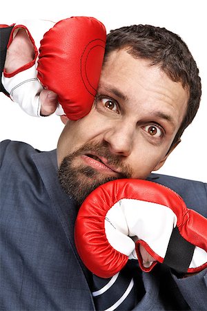 Close-up young businessman struck in the face by hands in red boxing gloves isolated on white background Stock Photo - Budget Royalty-Free & Subscription, Code: 400-06794171