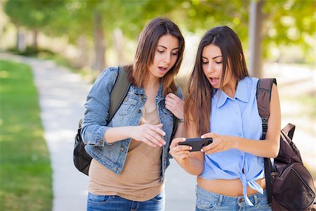 simsearch:400-05734883,k - Young Adult Mixed Race Twin Sisters Sharing Cell Phone Experience Outside. Stock Photo - Budget Royalty-Free & Subscription, Code: 400-06794519