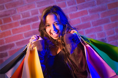 Excited Pretty Mixed Race Young Adult Woman Holding Shopping Bags with Brick Wall Background. Stock Photo - Budget Royalty-Free & Subscription, Code: 400-06794557