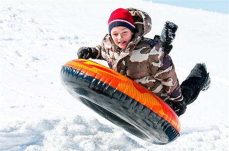 A happy boy up in the air on a tube sleding in the snow. Stock Photo - Budget Royalty-Free & Subscription, Code: 400-06794634