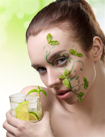 beauty portrait of cute brunette girl with creative green make-up and some mint leaves on the face, taking a cocktail mojito in hand Stock Photo - Budget Royalty-Free & Subscription, Code: 400-06795077