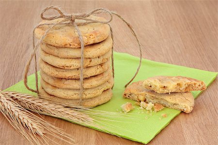 partially eaten - White chocolate chip cookie stack tied with string with half eaten biscuit and ears of wheat over green serviette and oak background. Stock Photo - Budget Royalty-Free & Subscription, Code: 400-06795274