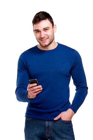 Attractive young man wearing a blue sweater and jeans stood holding a mobile phone isolated on a white background Stock Photo - Budget Royalty-Free & Subscription, Code: 400-06795734