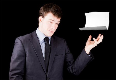 Businessman presenting a blank sheet of paper with room for text isolated on black Photographie de stock - Aubaine LD & Abonnement, Code: 400-06798643