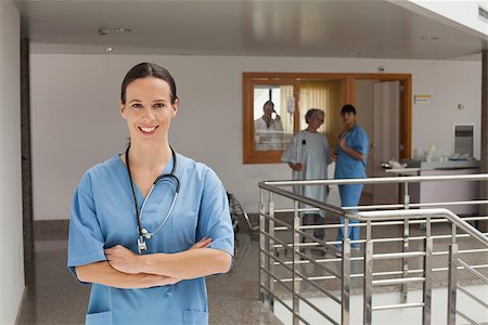 simsearch:400-06799599,k - Smiling doctor standing in the hallway of a hospital while crossing her arms Foto de stock - Super Valor sin royalties y Suscripción, Código: 400-06799504