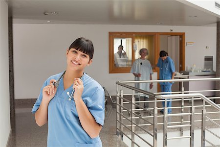 simsearch:400-06799599,k - Laughing doctor standing in the hallway while touching her stethoscope Foto de stock - Super Valor sin royalties y Suscripción, Código: 400-06799505