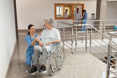 simsearch:400-06799497,k - Nurse smiling and kneeling beside old women sitting in wheelchair Stockbilder - Microstock & Abonnement, Bildnummer: 400-06799516