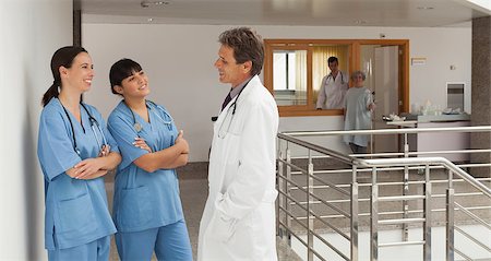 simsearch:400-06799497,k - Doctor and two nurses, standing in the hall of a hospital while talking and having fun Stockbilder - Microstock & Abonnement, Bildnummer: 400-06799510