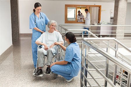 simsearch:400-06799497,k - Two nurses talking with old women sitting in wheelchair and smiling Stockbilder - Microstock & Abonnement, Bildnummer: 400-06799521