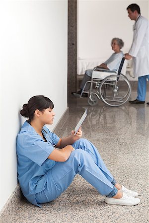 simsearch:400-06799497,k - Nurse reading sitting on floor in hospital corridor Stockbilder - Microstock & Abonnement, Bildnummer: 400-06799537