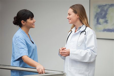 simsearch:400-06799599,k - Nurse talking and smiling with female doctor in hospital corridor Foto de stock - Super Valor sin royalties y Suscripción, Código: 400-06799567