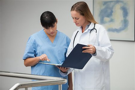 simsearch:400-06799497,k - Female doctor explaining notes to nurse and pointing in hospital corridor Stockbilder - Microstock & Abonnement, Bildnummer: 400-06799568