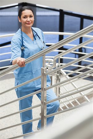 simsearch:400-06799599,k - Smiling nurse in a stairwell leaned on the railings in hospital corridor Foto de stock - Super Valor sin royalties y Suscripción, Código: 400-06799577