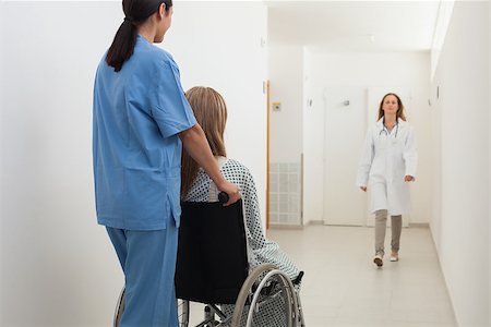 doctor pushing wheelchair - Nurse pushing patient in wheelchair with doctor approaching in hospital corridor Stock Photo - Budget Royalty-Free & Subscription, Code: 400-06799592