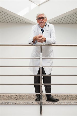 Doctor leaning on the railing with glasses with serious expression in hospital corridors Stock Photo - Budget Royalty-Free & Subscription, Code: 400-06799665