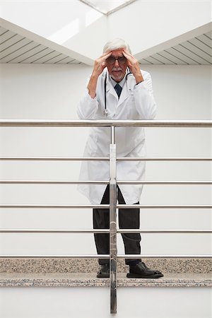 Stressed doctor is leaning on the railing with hands on his forehead while in hospital corridor Stock Photo - Budget Royalty-Free & Subscription, Code: 400-06799666