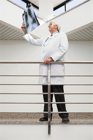 Doctor looking at x-ray leaning against railing in hospital corridor Stock Photo - Budget Royalty-Free & Subscription, Code: 400-06799667