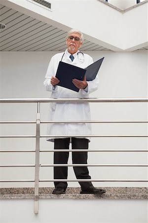Doctor standing on the railing watching his papers Stock Photo - Budget Royalty-Free & Subscription, Code: 400-06799669