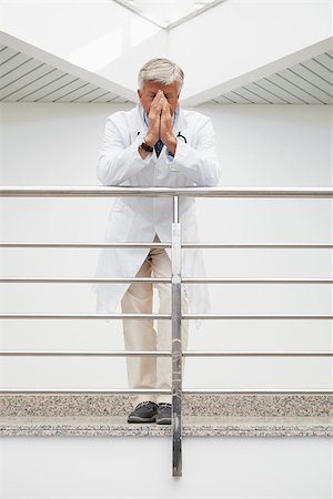 Worried doctor with face in hands leans against rail in hospital corridor Stock Photo - Budget Royalty-Free & Subscription, Code: 400-06799663