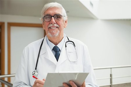 Doctor smiling in hospital corridor holding patient file Stock Photo - Budget Royalty-Free & Subscription, Code: 400-06799676