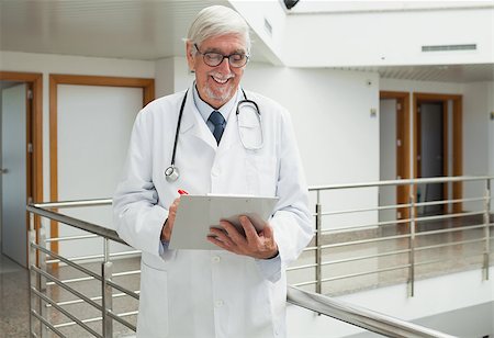 simsearch:400-06799497,k - Doctor smiling as he looks at patient file in hospital corridor Stockbilder - Microstock & Abonnement, Bildnummer: 400-06799678