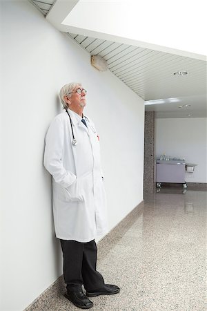 simsearch:400-06799599,k - Doctor leaning against white wall in hospital corridor Foto de stock - Super Valor sin royalties y Suscripción, Código: 400-06799680