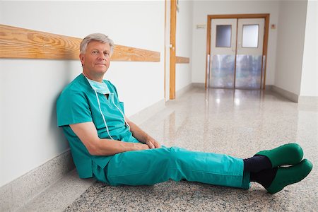 simsearch:400-06734621,k - Doctor sitting on the floor in the corridor smiling into the camera Stock Photo - Budget Royalty-Free & Subscription, Code: 400-06799709